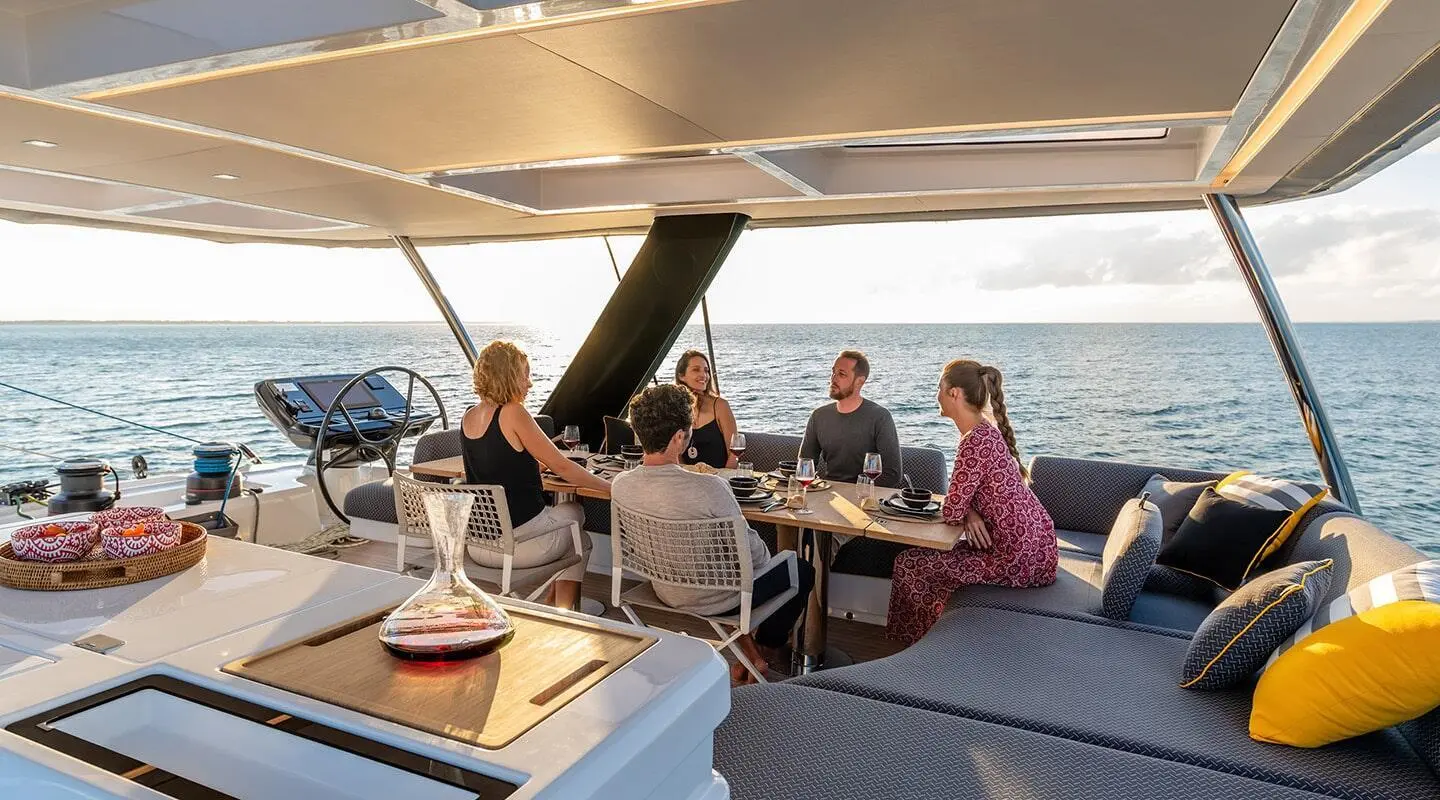 On the Daiquiri yacht, open sea, sunset, five people around a dining table