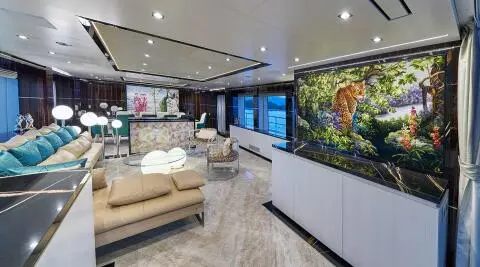 Interior of luxury yacht saloon with beige seating, wood floor, and bar