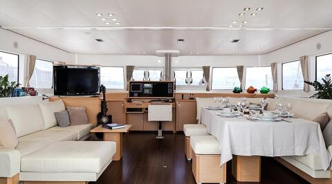 Aizu interior: bright salon and dining area onboard a luxury 30m yacht, cream seating, wooden accents, and formal table setup