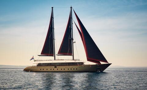 Anetta luxury 40m sailing yacht with dark sails and panoramic windows at sea