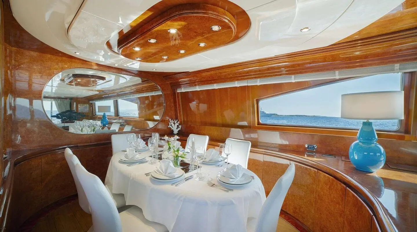Interior dining area aboard Zoi yacht with white table settings and wooden paneling