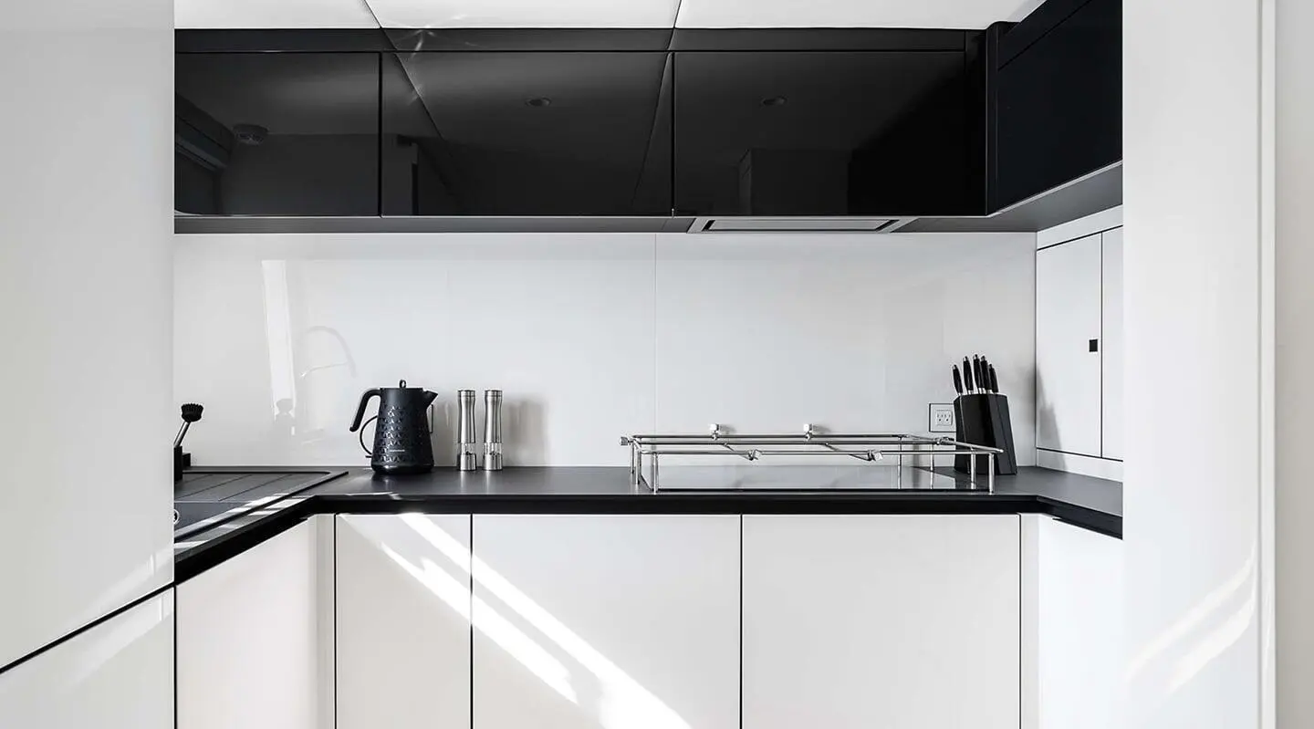 A sleek yacht kitchen with white cabinets, shelves, and a coffee maker.