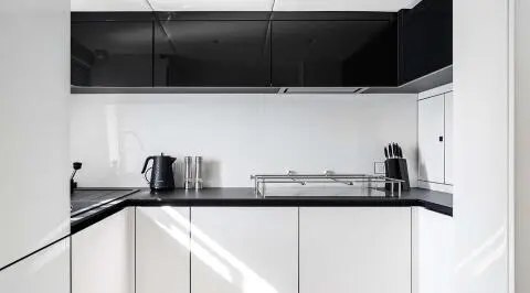 A sleek yacht kitchen with white cabinets, shelves, and a coffee maker.