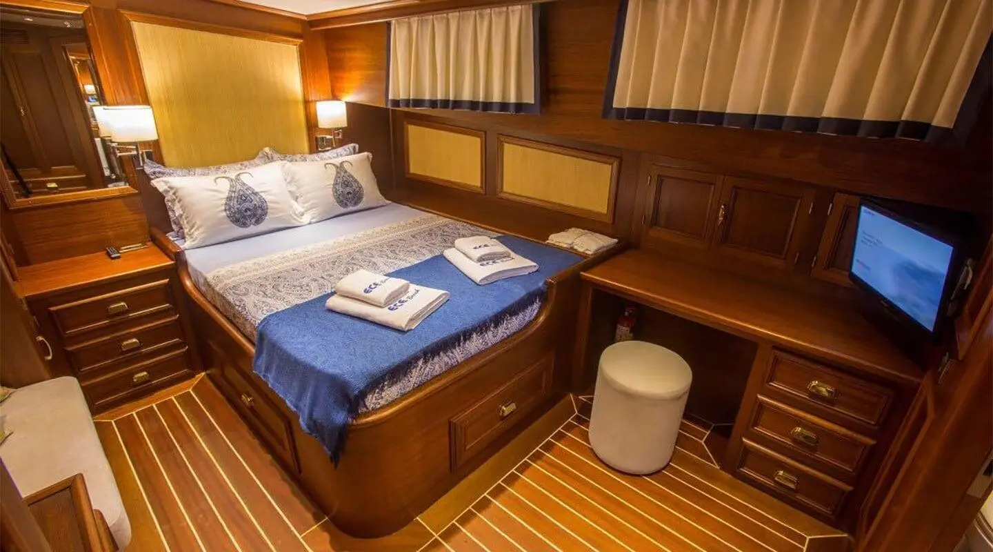 Interior of yacht Ece Berrak with wooden cabinets, bed, and blue bedding