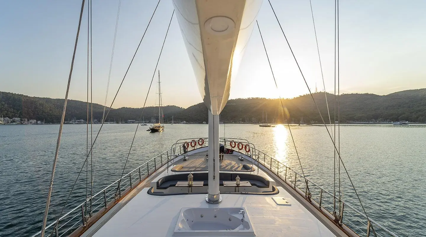 From the bow of Queen Of Makri, view toward sunset over calm sea and rigging