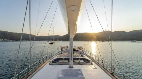 From the bow of Queen Of Makri, view toward sunset over calm sea and rigging