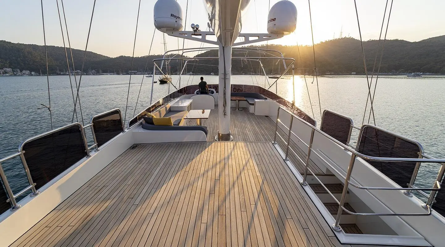 Deck view of Queen Of Makri sailing at sunset, teak planks and rigging visible