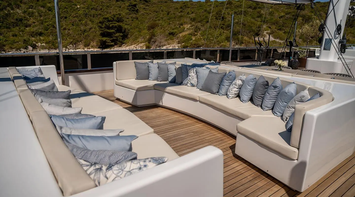 Anima Maris yacht deck lounge with white seating and wooden flooring