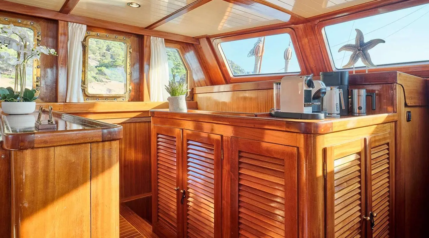 Sunset-lit deck of Myra yacht; polished wooden railing and seating area