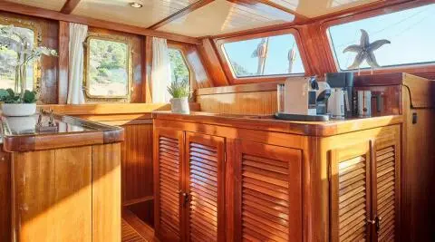 Sunset-lit deck of Myra yacht; polished wooden railing and seating area