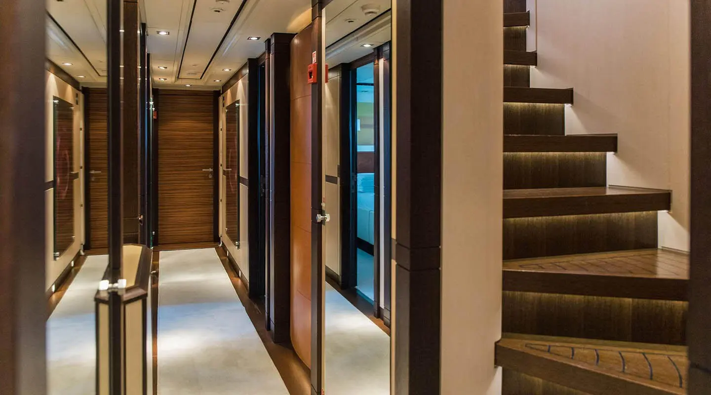 Luxurious interior corridor of Alalya yacht with wood accents and illuminated staircase