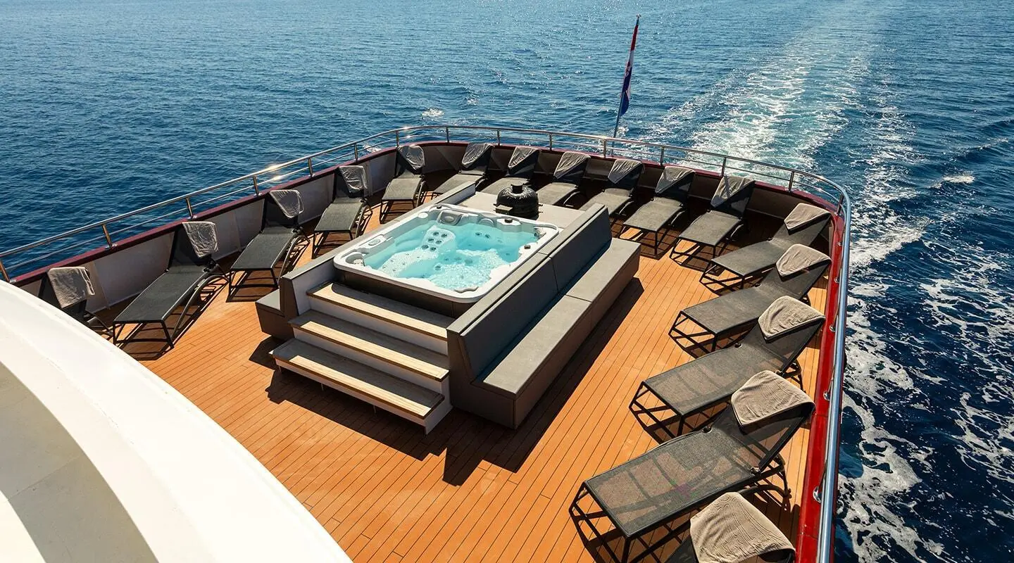 Yacht YOLO deck with hot tub and lounge chairs on teak harbor view