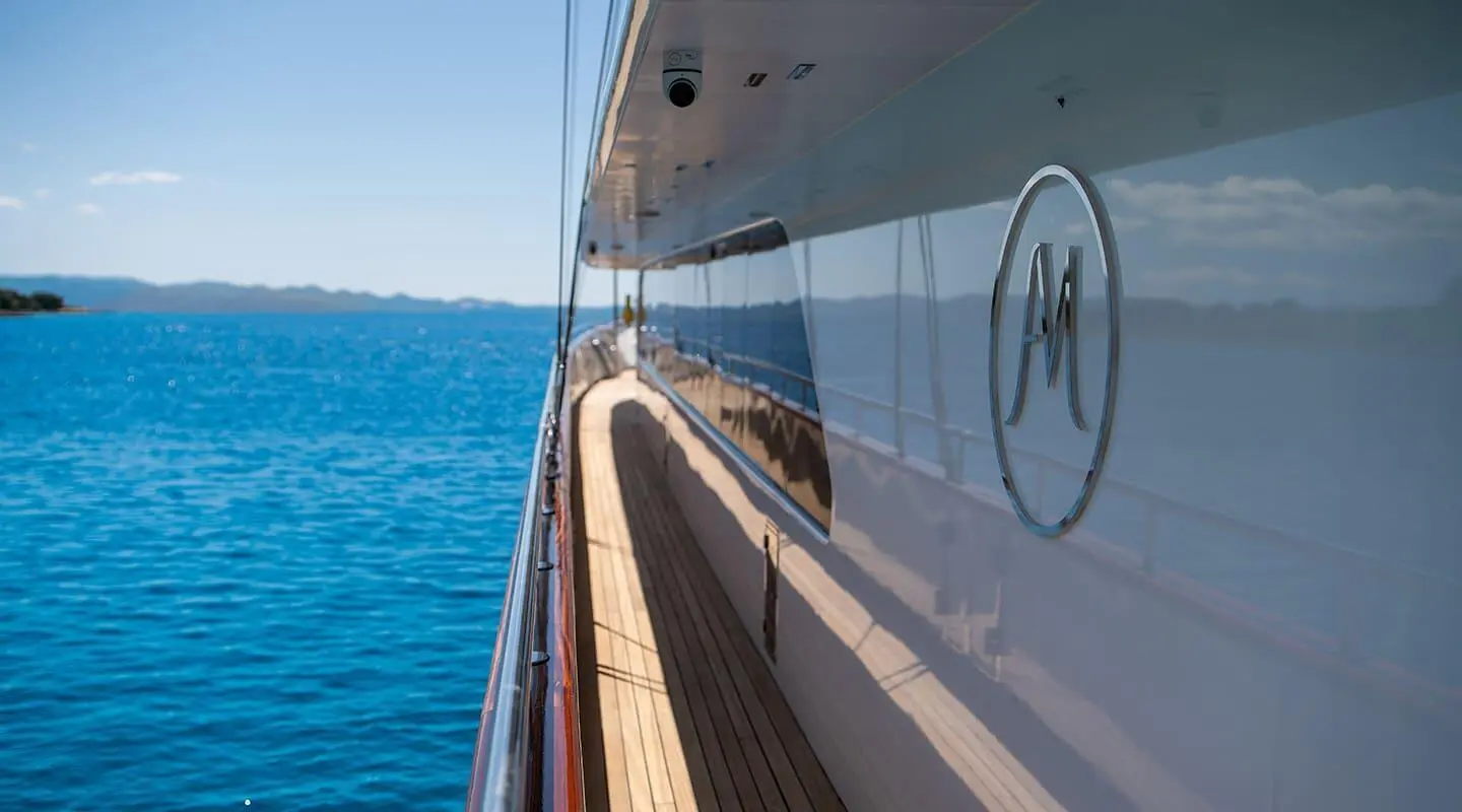 Side view of Anima Maris yacht anchored by clear blue sea with reflection
