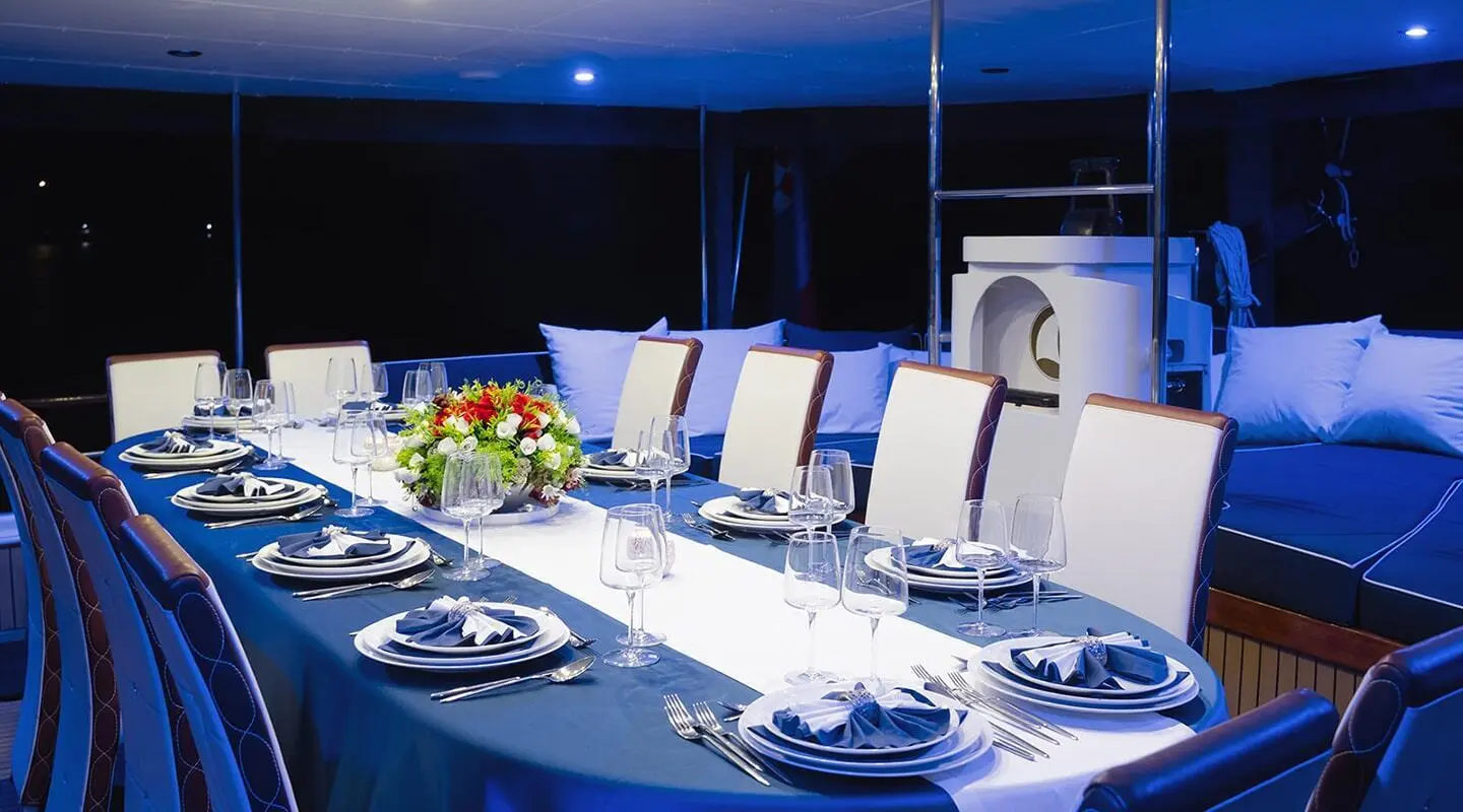 Auryum yachts dining area aboard Aurum at sunset with plated table setup