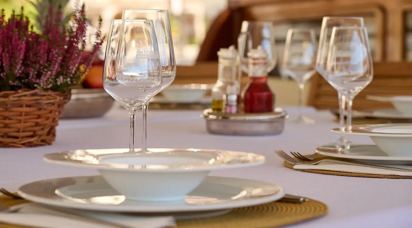 Elegant dining setup on a yacht with glassware and plates under sunlit deck