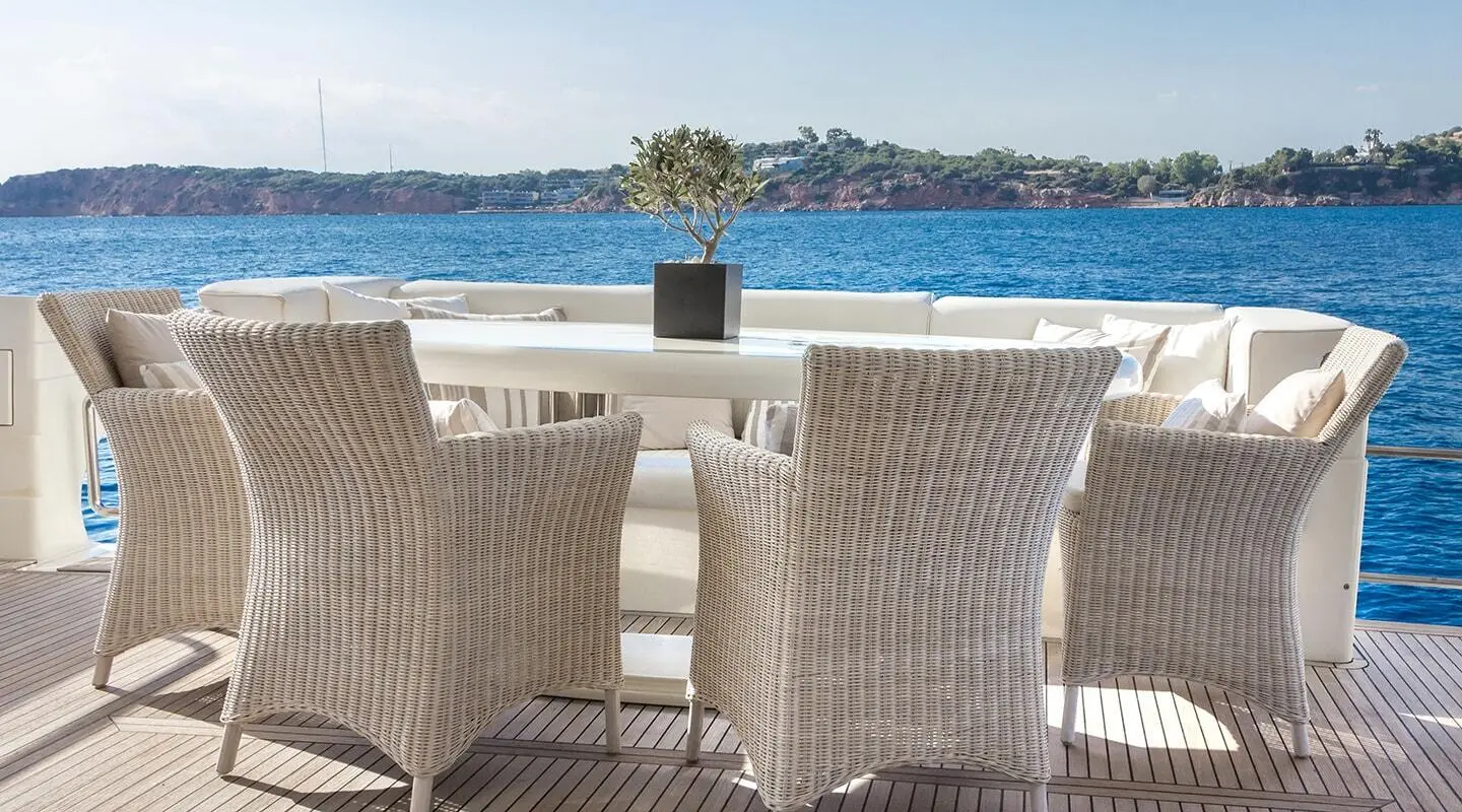 Amoraki yacht dining setup on deck at sunset with wicker chairs and table