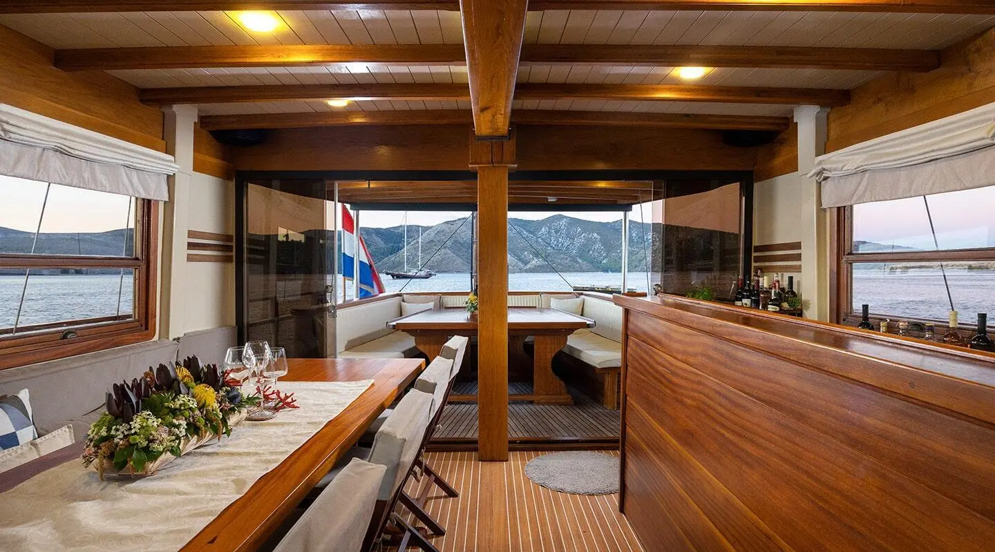 Wide view of Aborda yacht deck at sunset with wooden seating and table