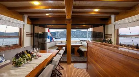 Wide view of Aborda yacht deck at sunset with wooden seating and table