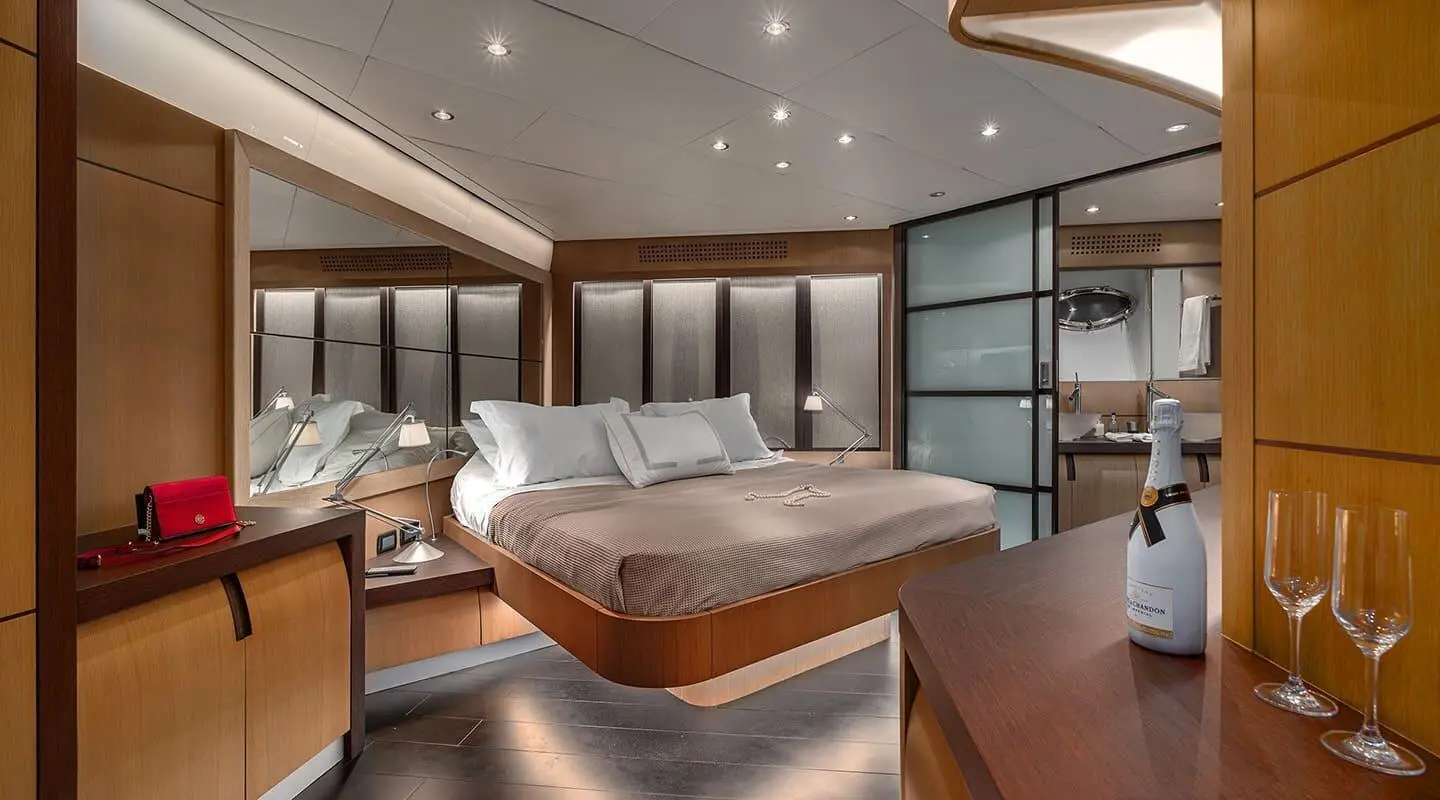 Luxurious yacht One master cabin with large bed, wood tones, and porthole view