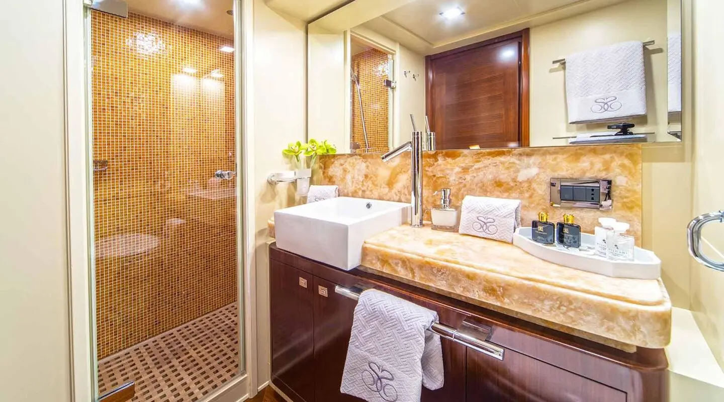 Luxurious yacht bathroom with circular mirror, wood cabinetry, and beige towels