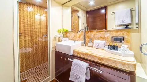 Luxurious yacht bathroom with circular mirror, wood cabinetry, and beige towels
