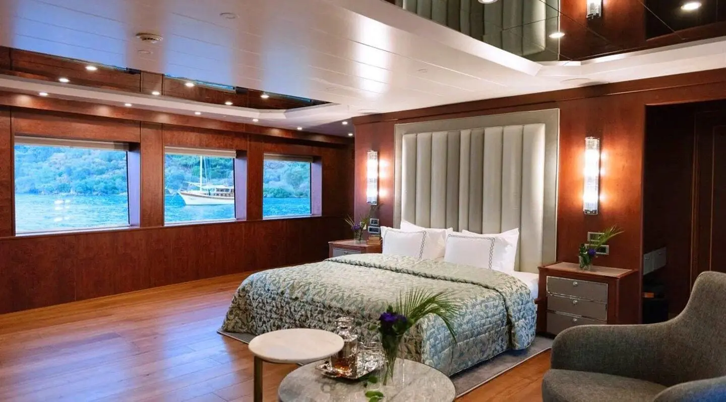 Interior bedroom aboard Ocean Breeze yacht with bed, windows, and seating
