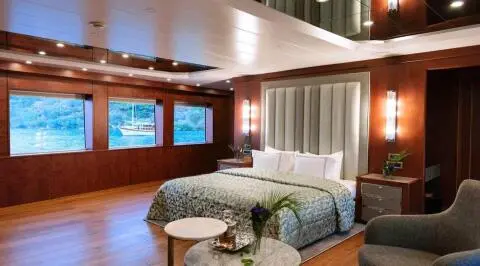 Interior bedroom aboard Ocean Breeze yacht with bed, windows, and seating