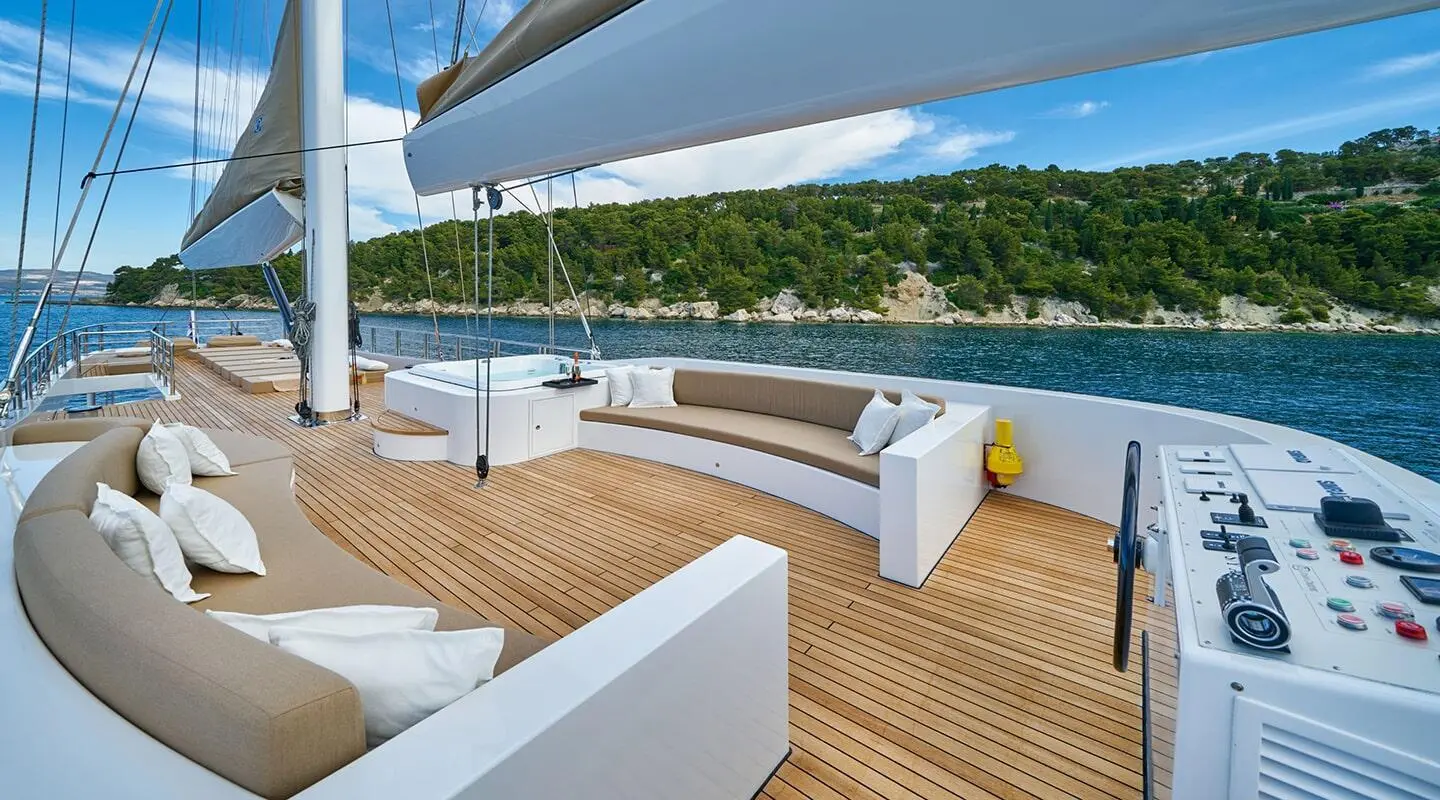 Acapella motor yacht outdoor deck with white seating and blue sails