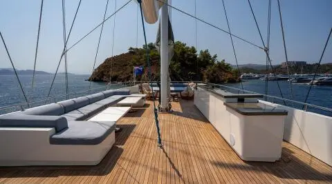 Deck view of De Love yacht with lounge seating and small island nearby