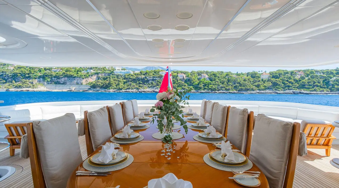 Elegant yacht dining setup on Apogee with white napkins and flowers onboard