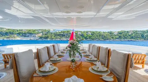 Elegant yacht dining setup on Apogee with white napkins and flowers onboard