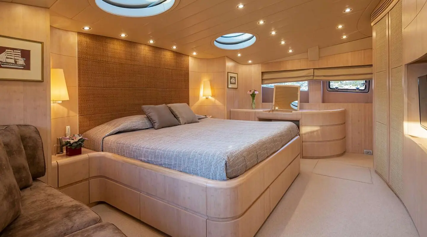 Glaros yacht bedroom with double bed, wooden cabinets, and seating
