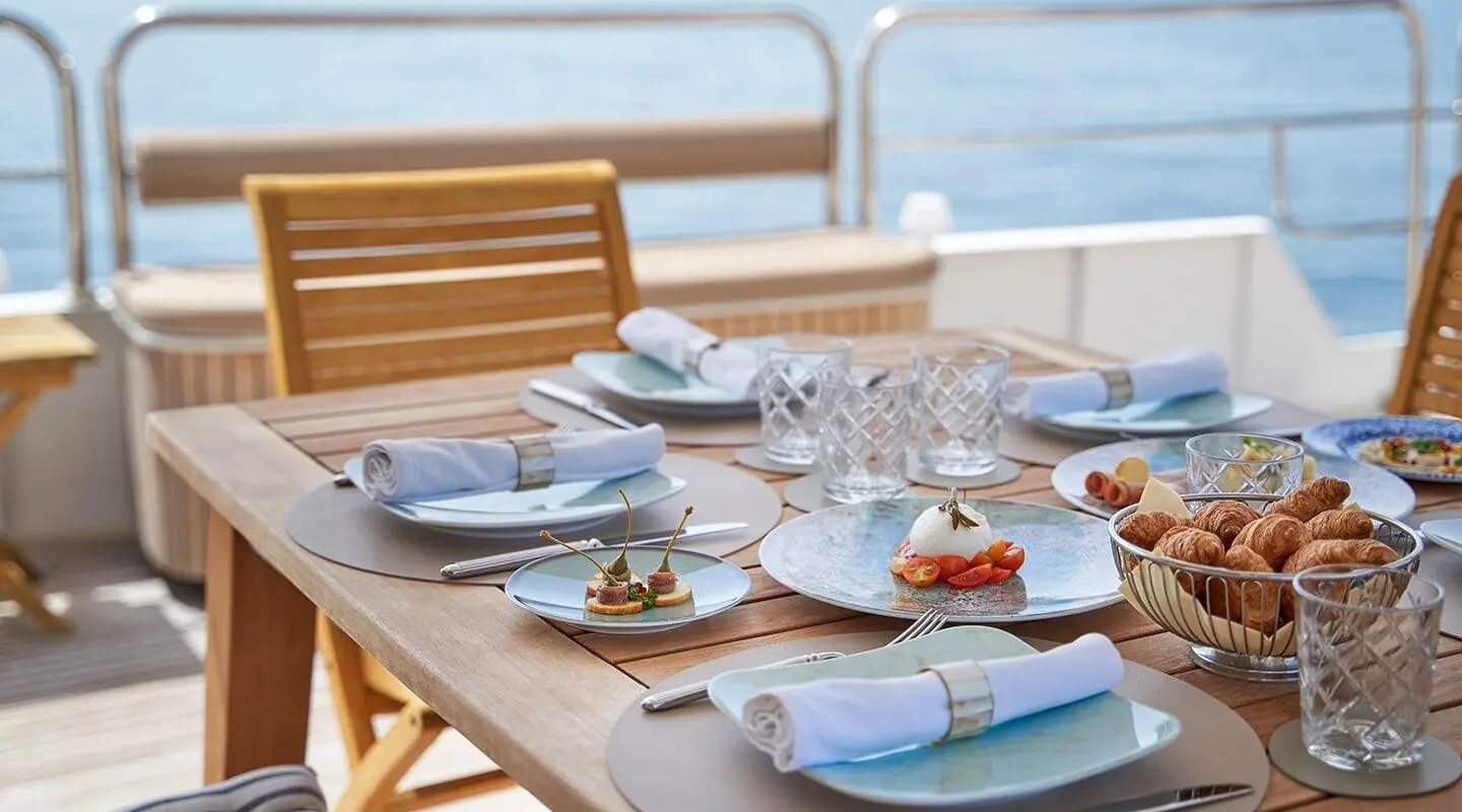 La Perla yacht dining table set with plates, glasses, and sea view