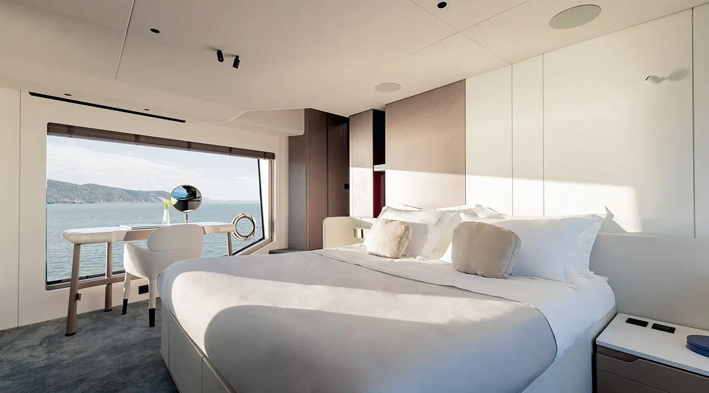 Viva II luxury yacht cabin with king bed, large window view of sea, seating desk area
