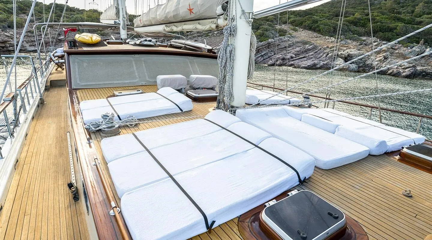 Sunset over a luxury gulet yacht deck with white cushions and wooden railings