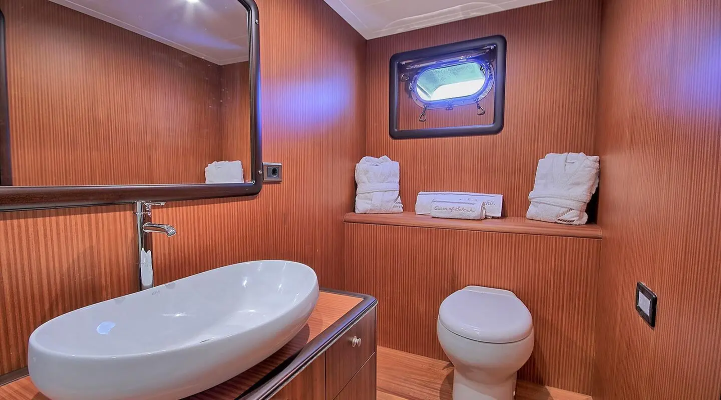 Yacht bathroom with wood paneling, white towels neatly folded on shelf