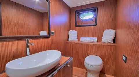 Yacht bathroom with wood paneling, white towels neatly folded on shelf
