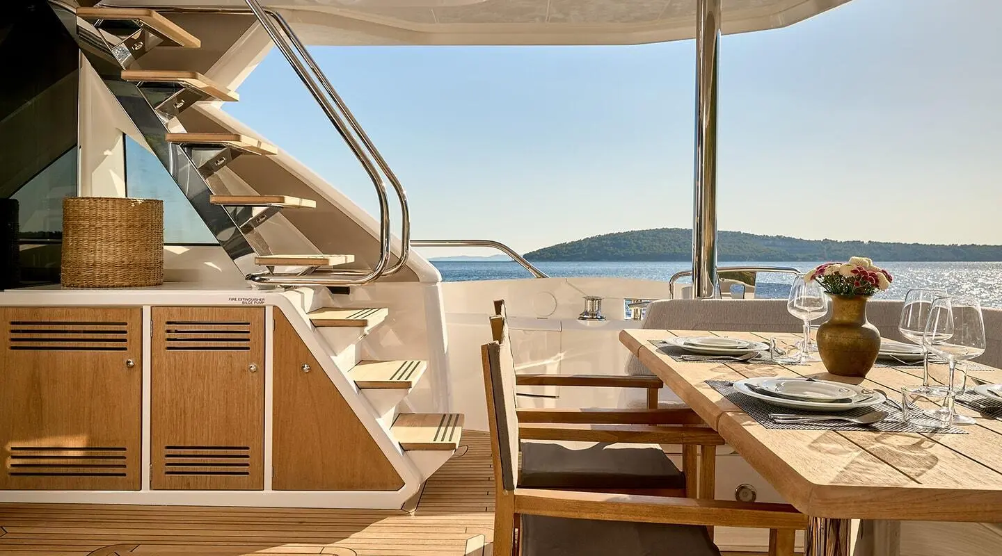 Aft dining area on a luxury yacht with wooden stairs and ocean view