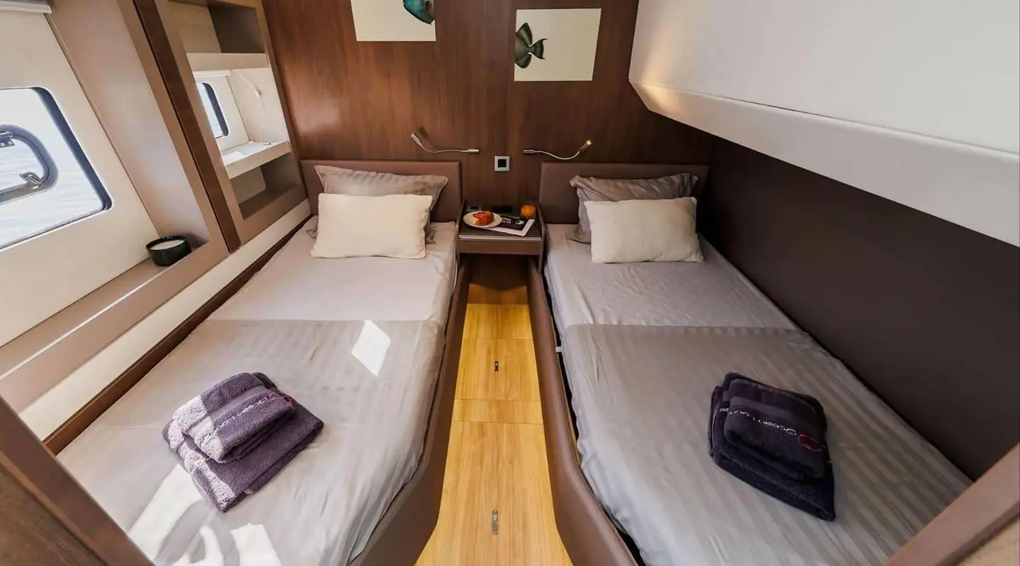 Interior of Ocean Lounge yacht with twin beds and wooden floor accent