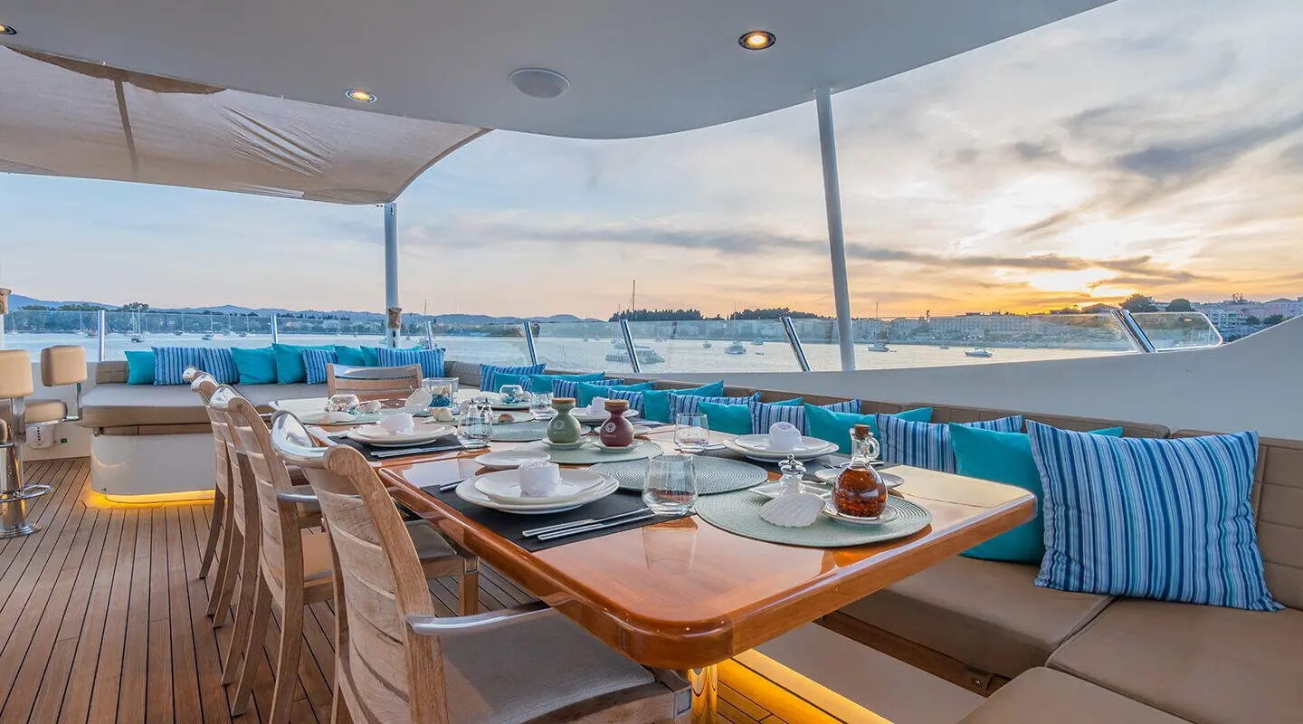 Serenity yacht dining area on deck at sunset with tables and chairs, ocean view