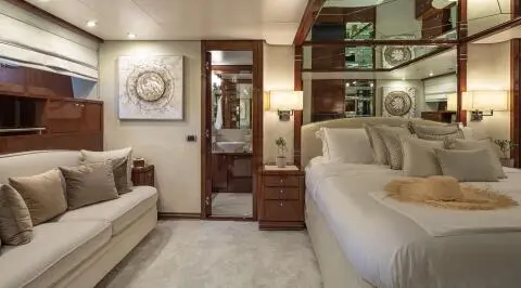 Grace yacht bedroom interior with bed, wooden furniture, and beige decor