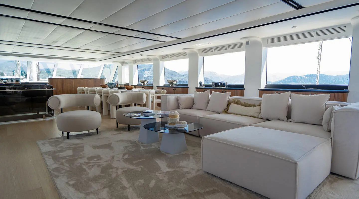 Lounge area aboard De Love yacht with white couches and sunlit windows
