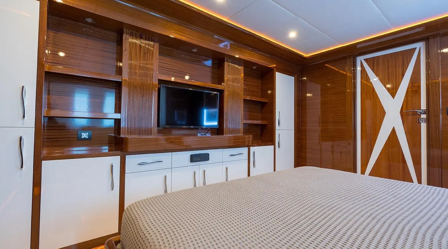 Bedroom interior with dark wood panels, TV and white cabinets