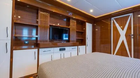 Bedroom interior with dark wood panels, TV and white cabinets