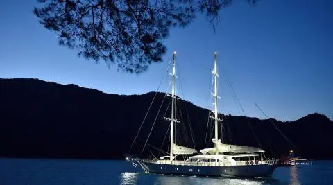 Alessandro I yacht anchored at sunset with calm blue water and hills