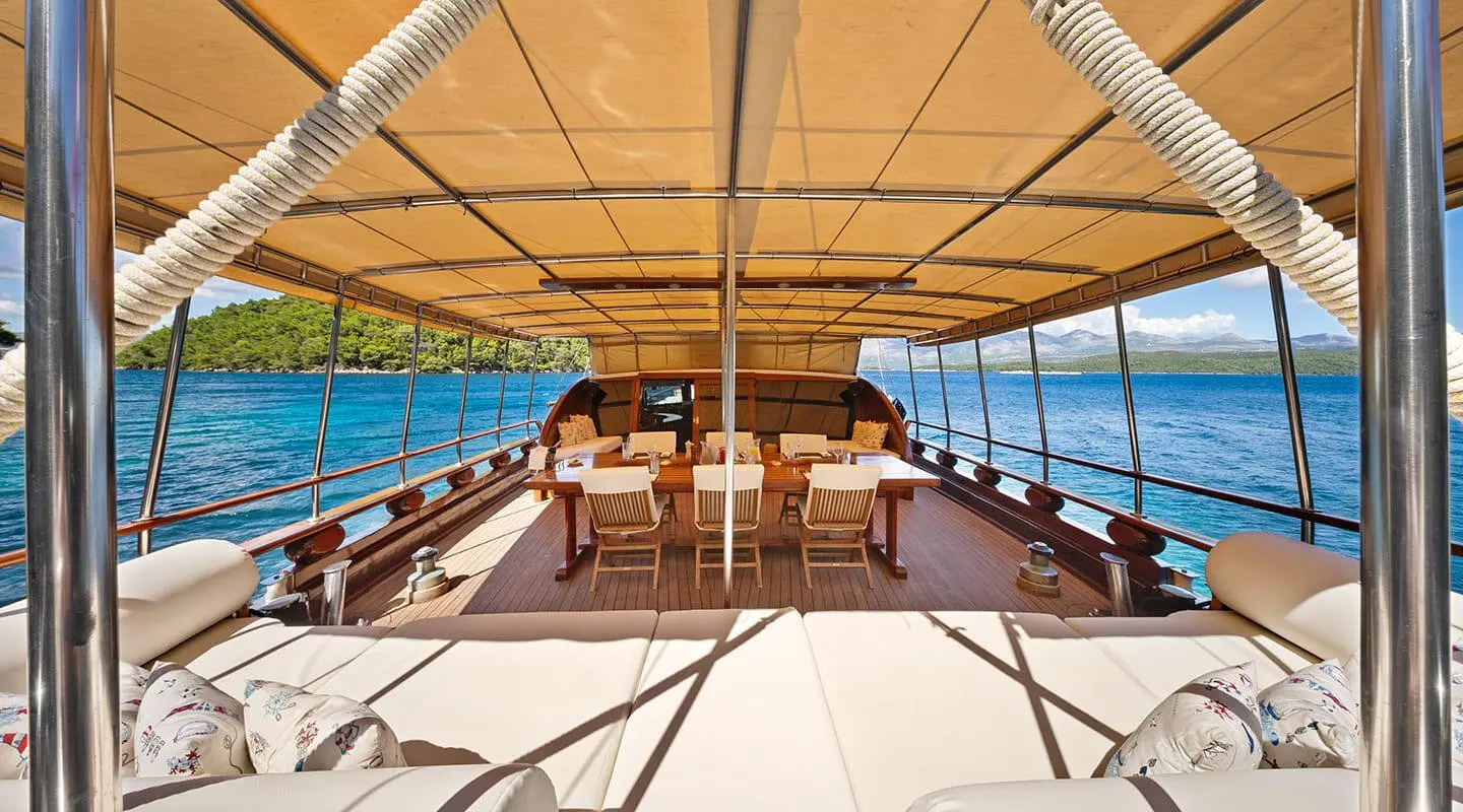 Eleganza yacht deck shaded by canopy with sunlight on teak and ocean view