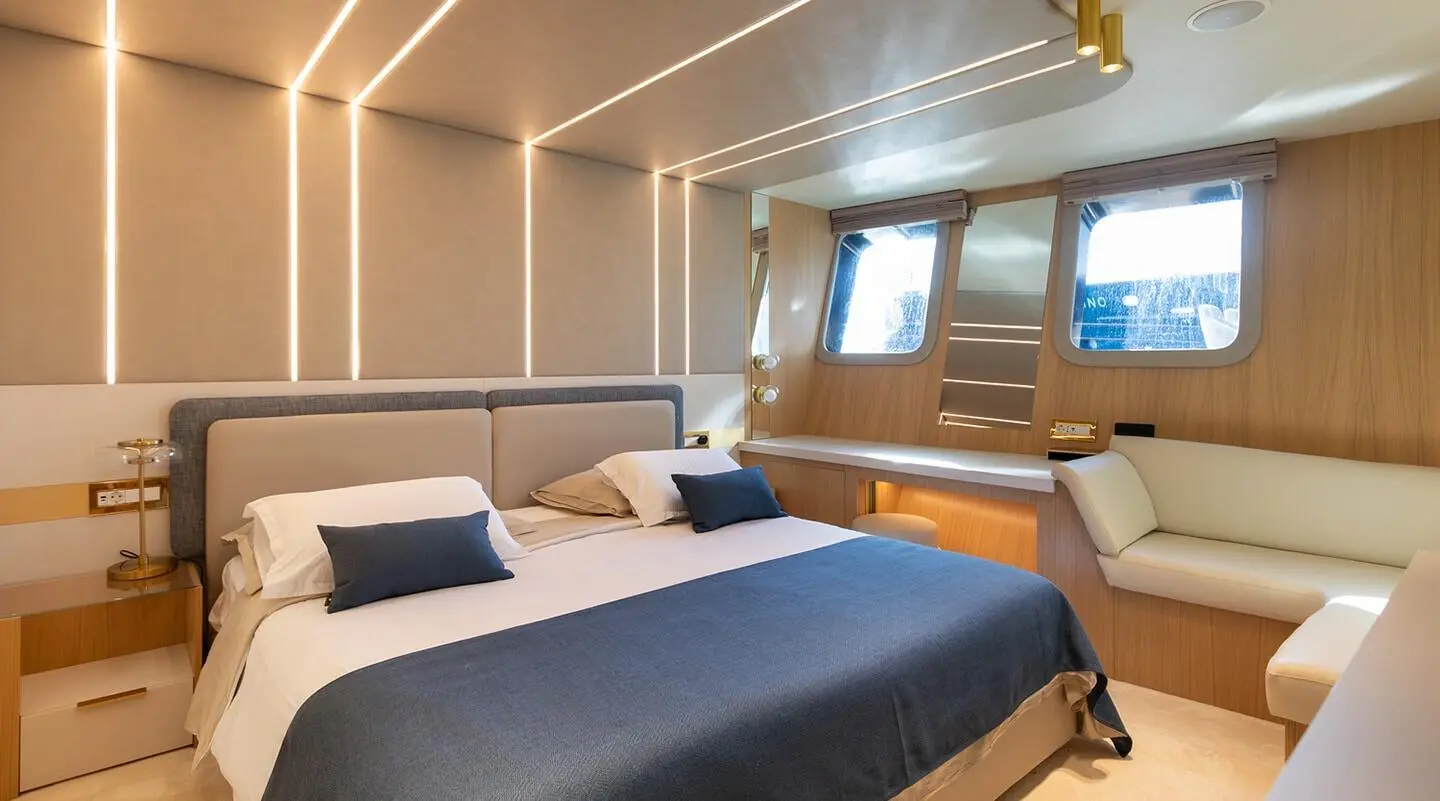 Two neatly made beds in a luxury yacht cabin with beige walls and large window