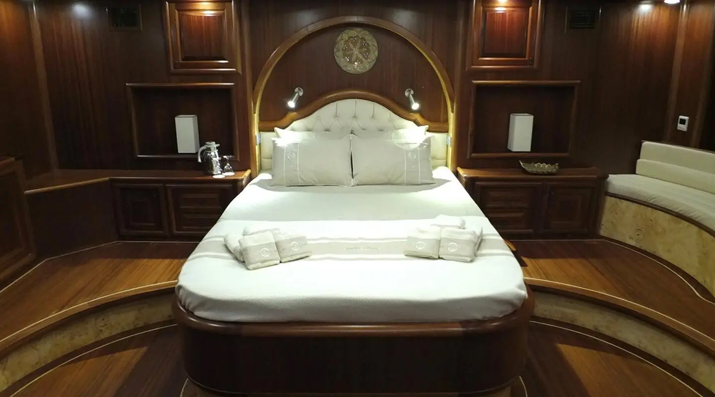 Wood-paneled cabin with white bed, headboard, and built-in nightstands