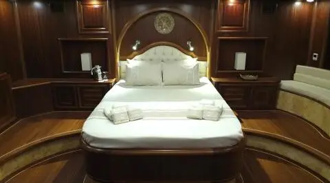 Wood-paneled cabin with white bed, headboard, and built-in nightstands