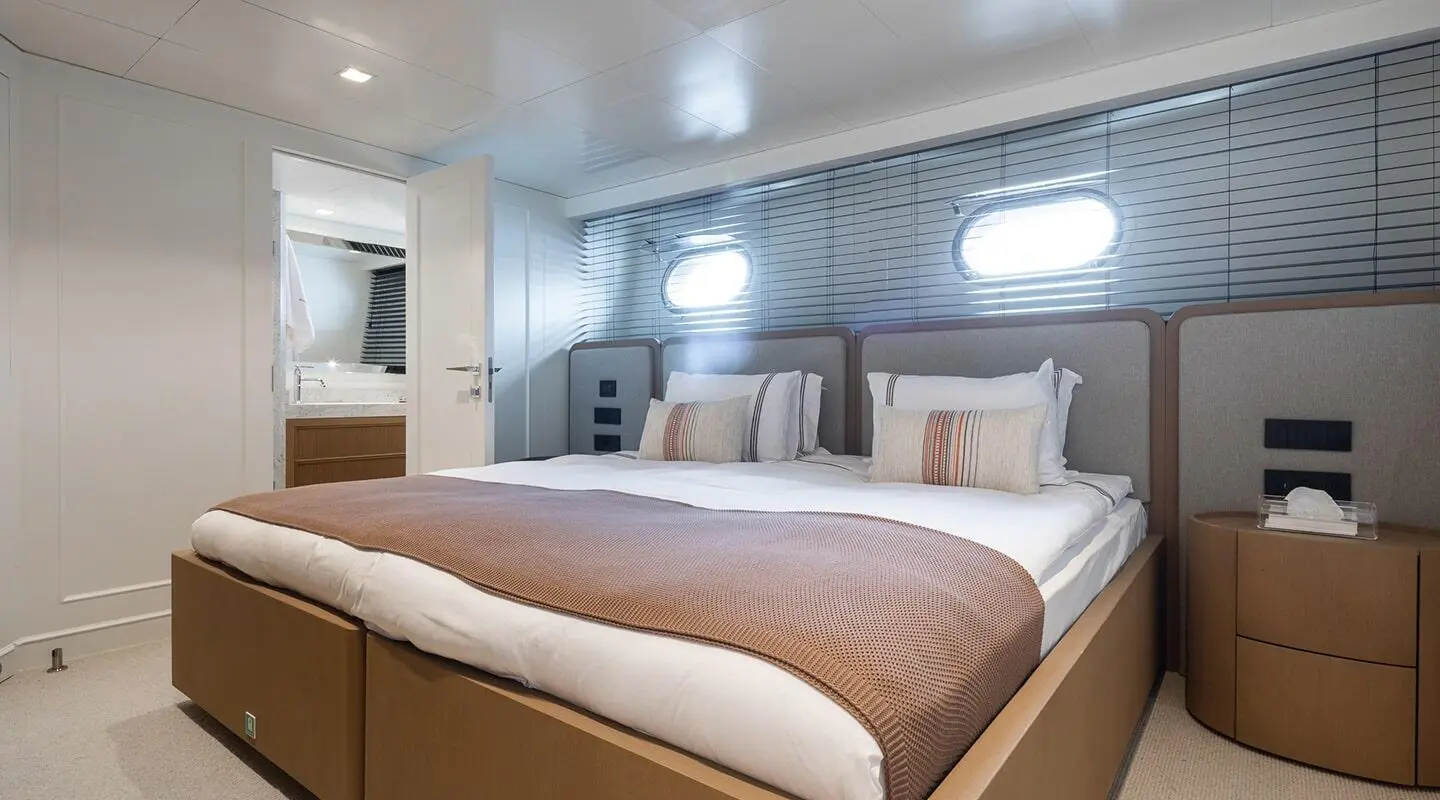 Illusion II yacht bedroom with brown accents, white bedding, and soft lighting